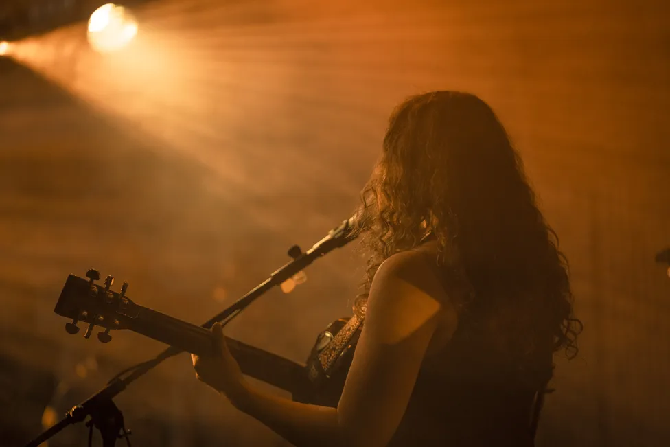Corinna Böhm singt mit Gitarre auf einer Bühne